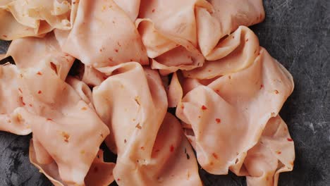 ham italian mordatella, man slices of traditional italian antipasti mortadella sausage on a wooden cutting board, close up macro of chicken or turkey jamon, fat breakfast dish.