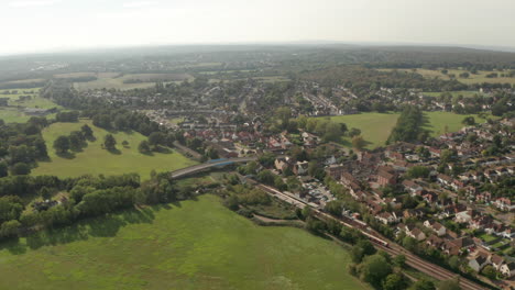 Circling-aerial-shot-of-train-leaving-Theydon-Bois-train-station