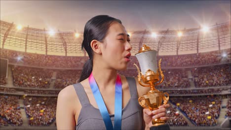 woman athlete celebrating victory with trophy in stadium