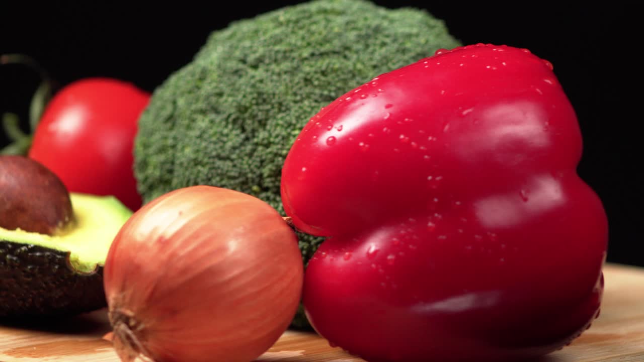 Close up of colorful vegetables rotating on a wooden board on a black background