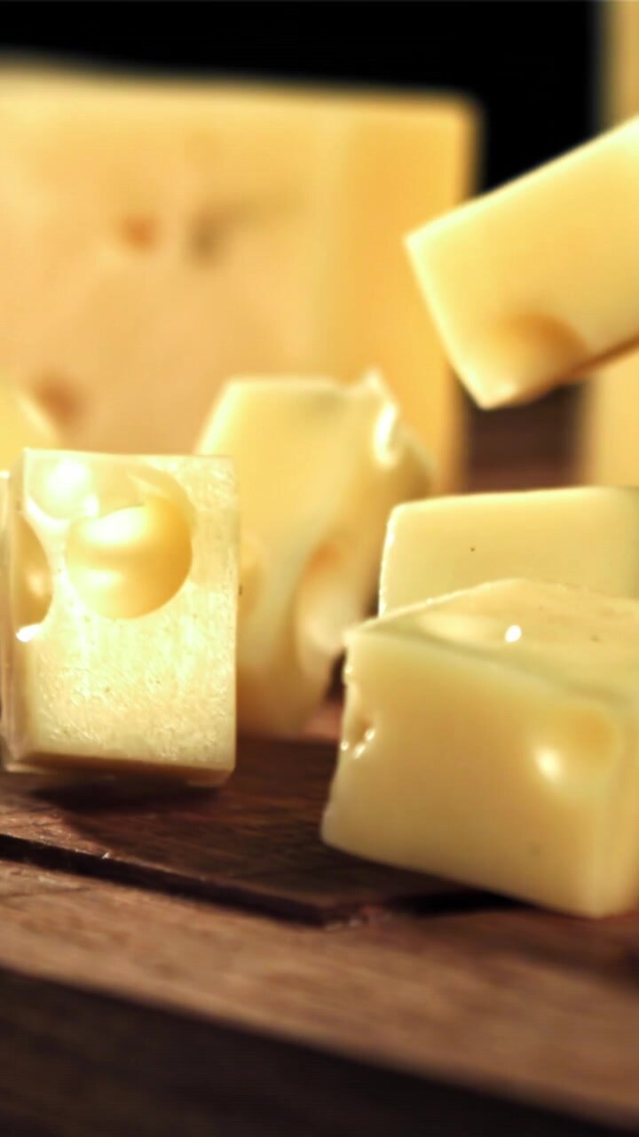 Slow Motion Yellow Cheese Cubes Falling onto a Wooden Board