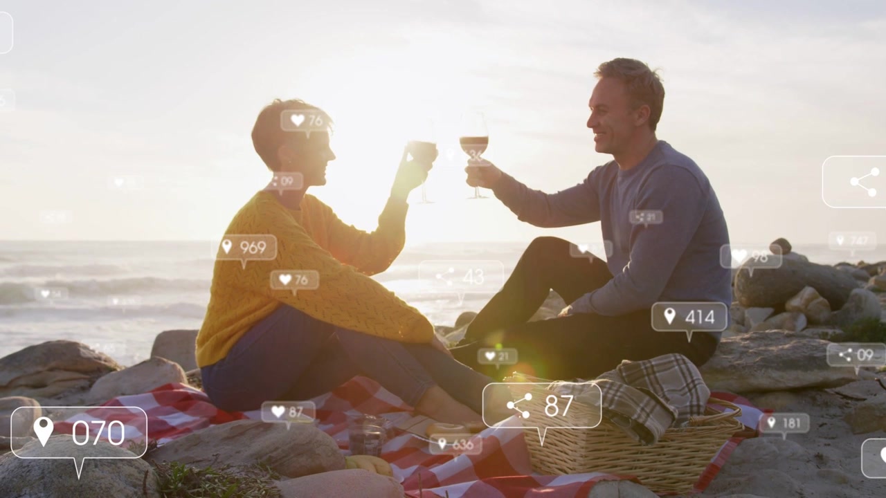 Couple sitting blanket shore clinking glasses cheering sparking social media heart counts rising