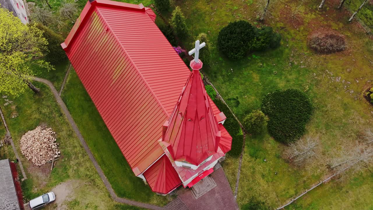 Rucava Lutheran Church stands out with red rooftop amid rural greenery, Latvia