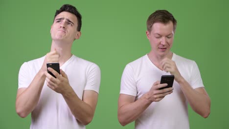 two young handsome men thinking while using phones together