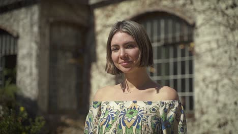 Una-Grabación-De-Mano-De-Una-Mujer-Joven-Que-Sonríe-Sutilmente-A-La-Cámara-Mientras-Disfruta-Del-Sol-A-Plena-Luz-Del-Día