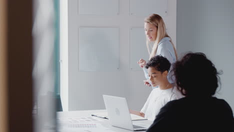 View-Through-Door-As-Female-Boss-Gives-Presentation-To-Team-Of-Businesswomen-Meeting-Around-Table