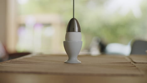 placing an boiled egg on a wooden table with placesets