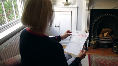 an unrecognizable senior woman worried about debts opening a debt letter