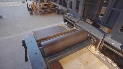 man carefully smoothing out wood shelf in industrial wood planer