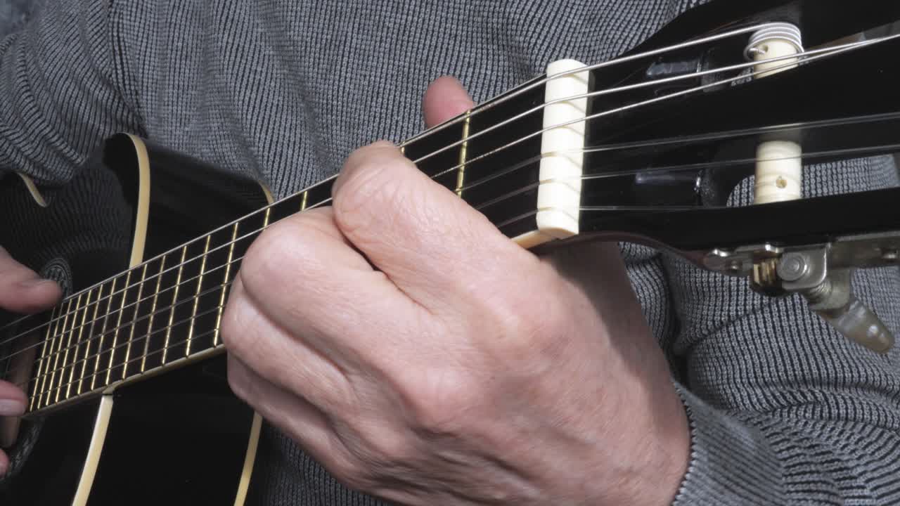 Senior man playing guitar at home. Close up