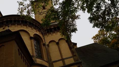 Shot-through-a-bush-of-a-bright-church-with-a-monastery-in-Germany-in-good-weather-with-many-arches-and-a-dark-window