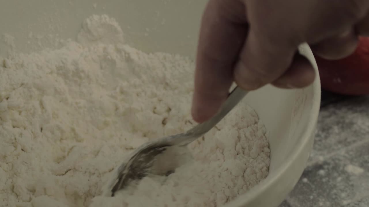 Hand Mixing flour with a spoon in a bowl medium shot