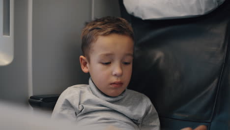 niño usando una tableta pc tratando de entretenerse durante un aburrido viaje en tren