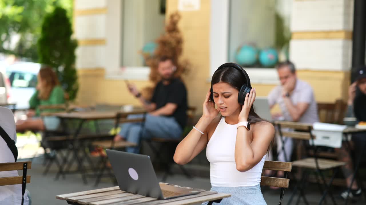Young Woman Listening to Music and Working in a Cafe