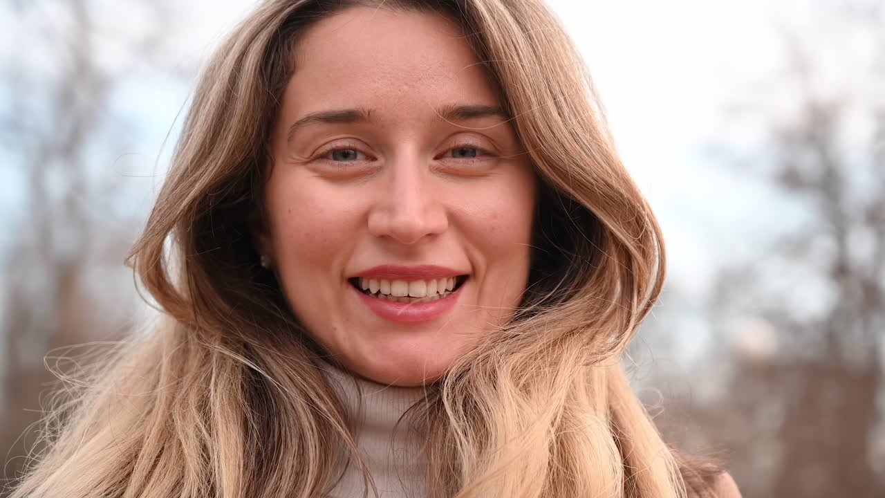 Close up of a blonde woman smiling in a park in daylight