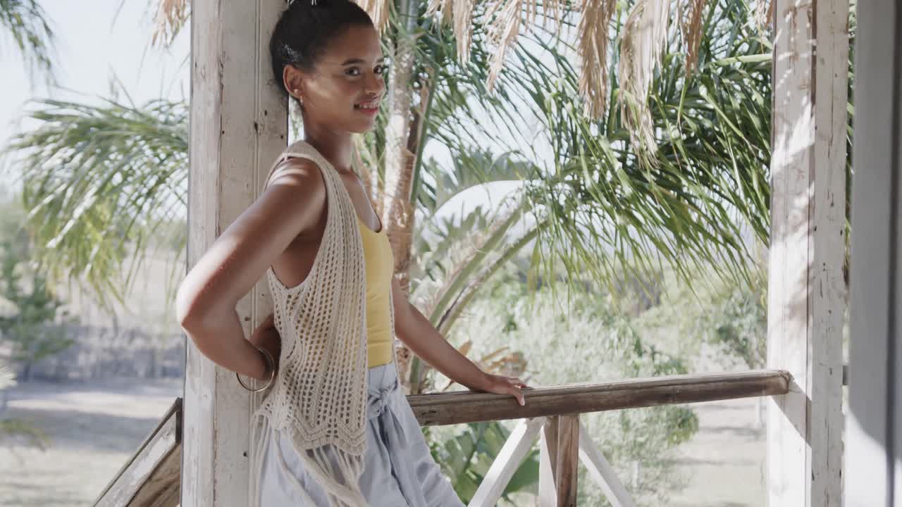 una pareja feliz y diversa relajándose en el porche de una casa de playa soleada, en cámara lenta