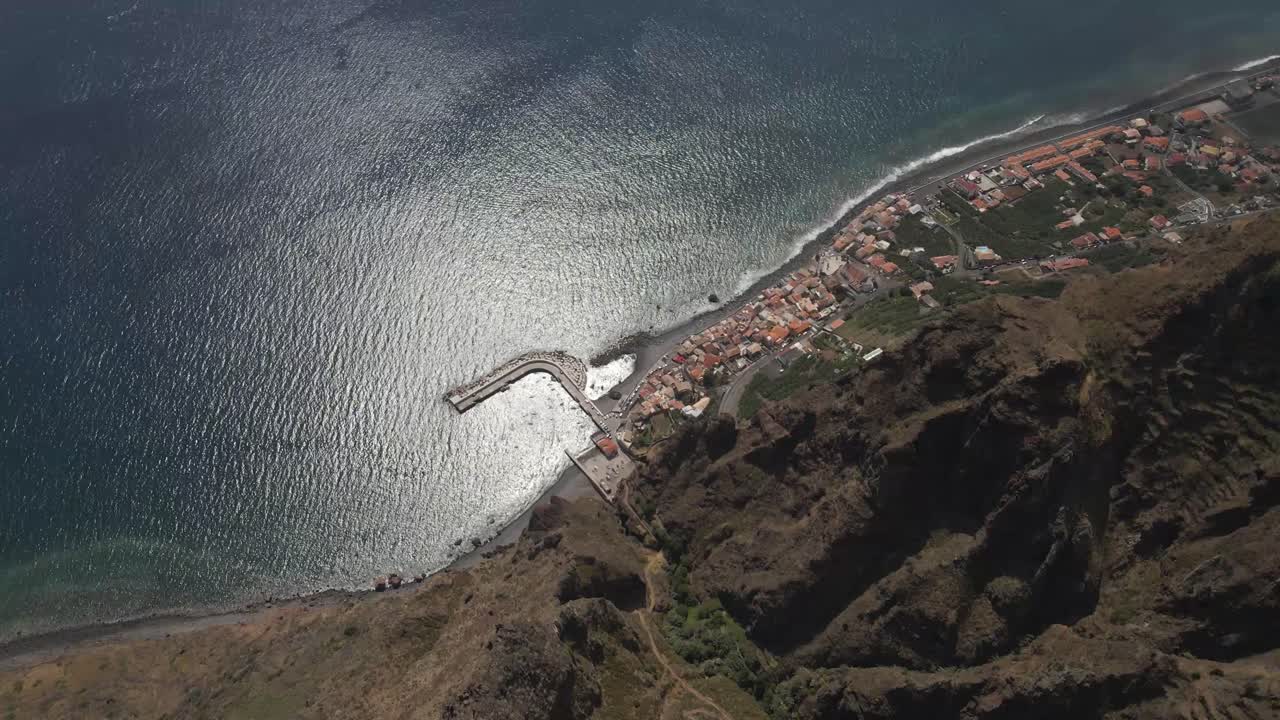 vista aérea de la parroquia de calheta en la isla de madeira, drone girando mostrando el contraste entre el pueblo cerca del mar y las montañas en el fondo-1