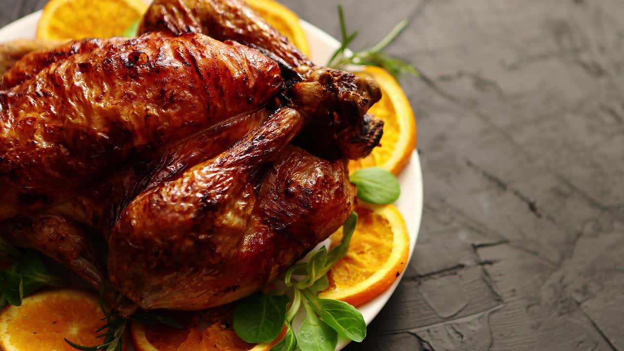 pollo o pavo entero asado servido en plato de cerámica blanca con naranjas