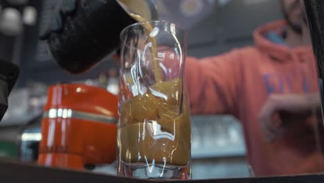 barista pours freddo espresso slow motion into curvy glass