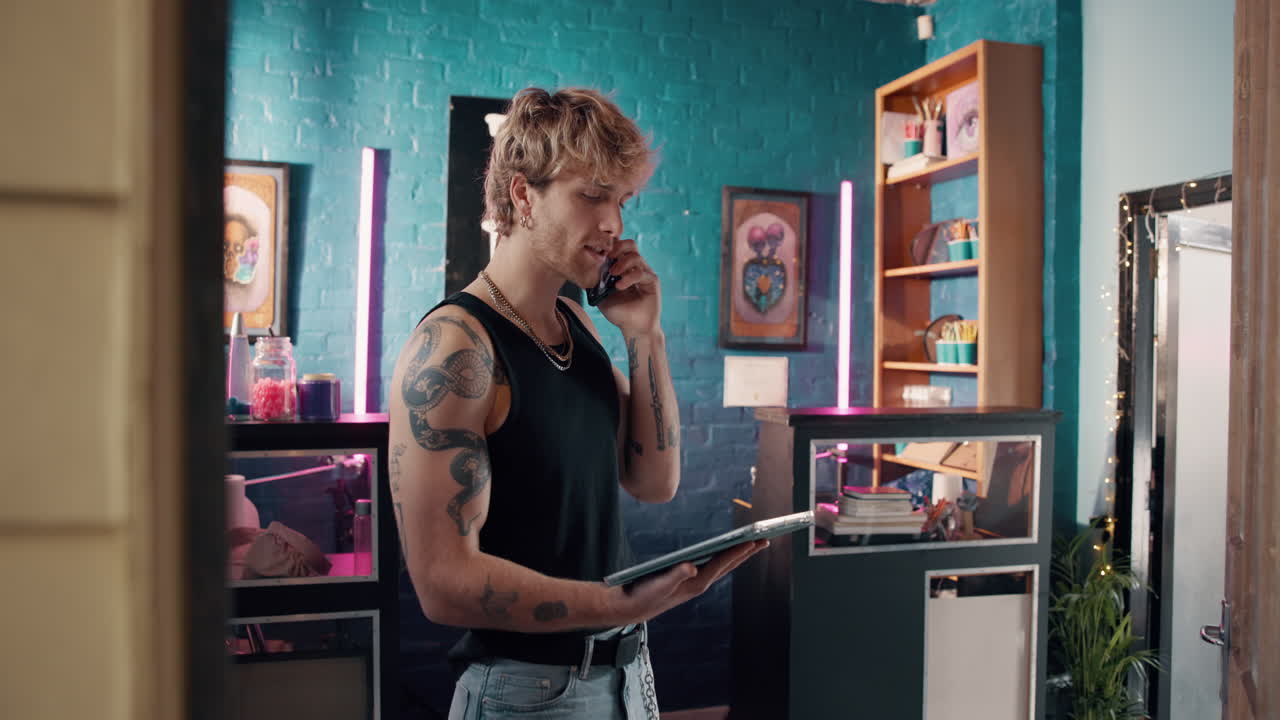 Man with Tattoos on Phone Call in Tattoo Studio