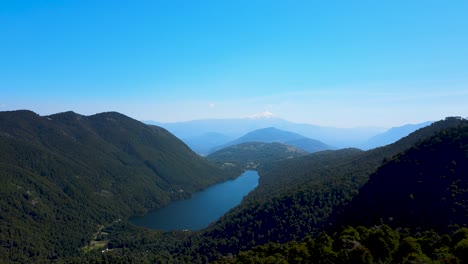 Aerial-dolly-in-of-Tinquilco-lake-between-Andean-mountains-covered-in-green-rain-forest,-Huerquehue-National-Park,-Chile