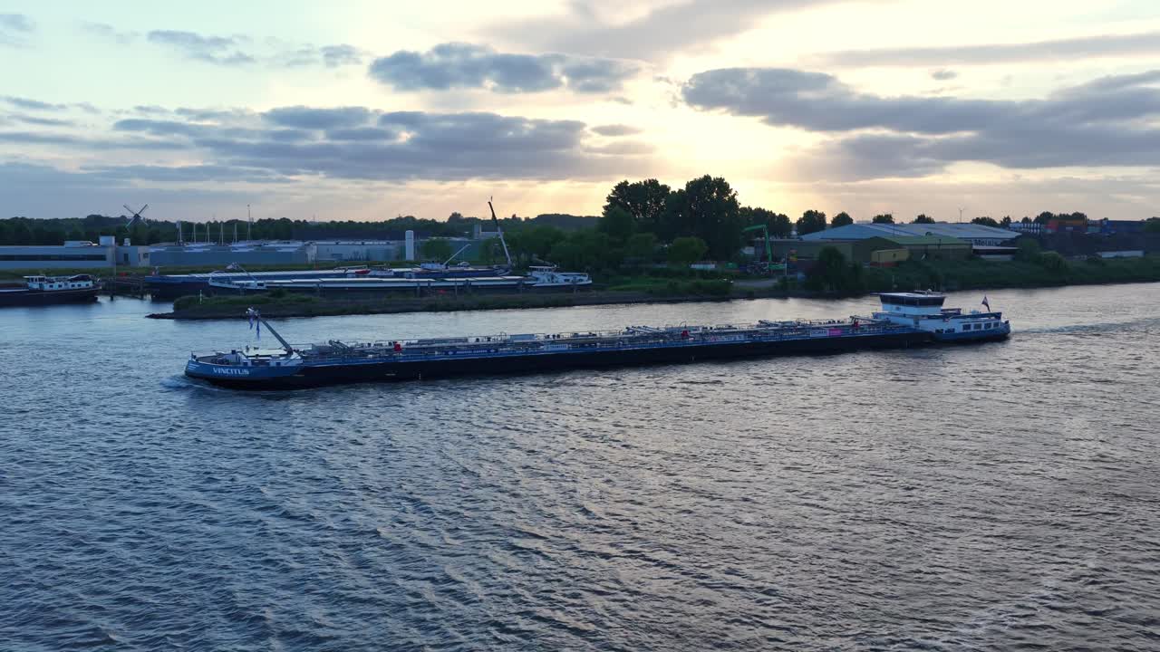 Cargo ship sails at sunset near Dordrecht, calm river reflecting light