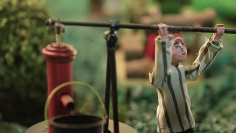 nativity figurine pumping water into a bucket with a red hand pump in a rural scene