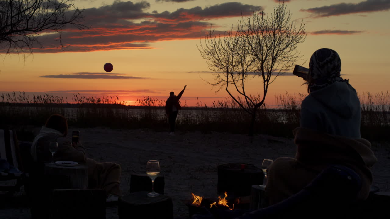 해가 지는 바다 해안선 배경에 친구 그룹 파티 해변. 피크닉에 가족.