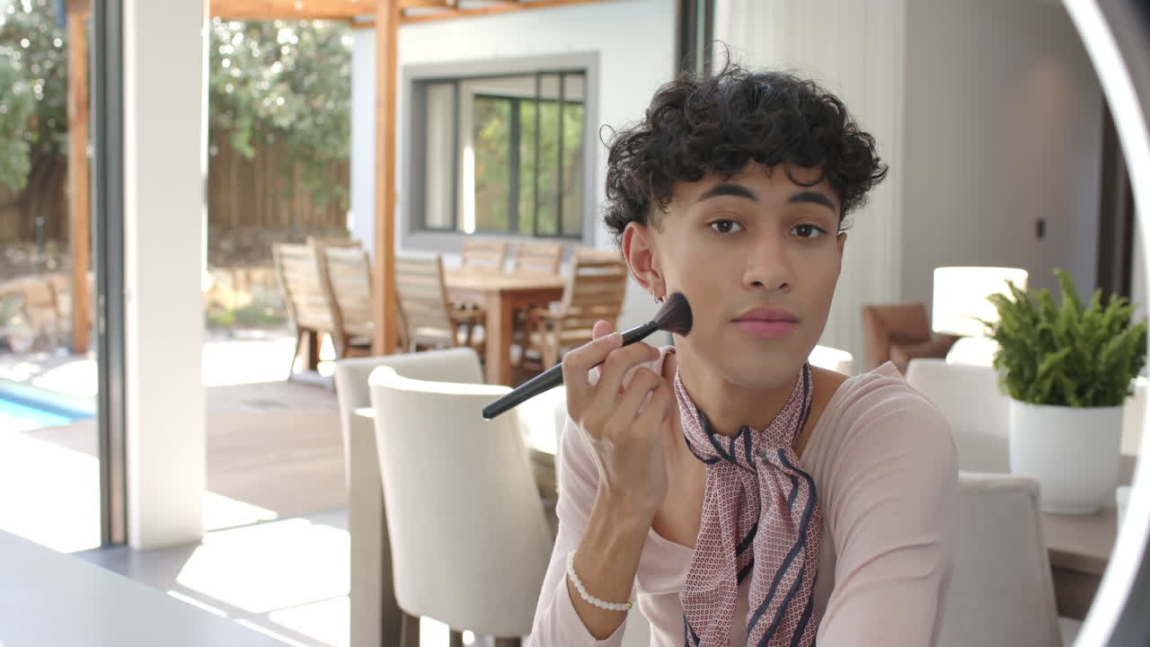 Applying makeup with brush, non binary person sitting at home near dining area