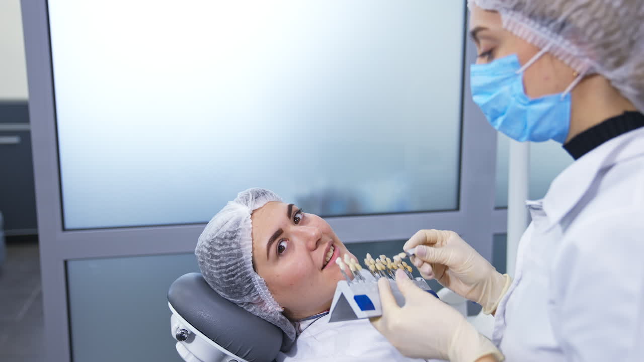 Dentistry student trying to find the sample of tooth color according to the patient's teeth. Two students at practical lessons.