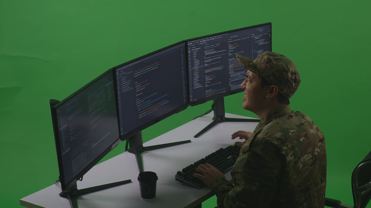 Side View Of Asian Man Soldier Developer Having Backache While Write Code With Multiple Computer Screens In Green Screen Studio