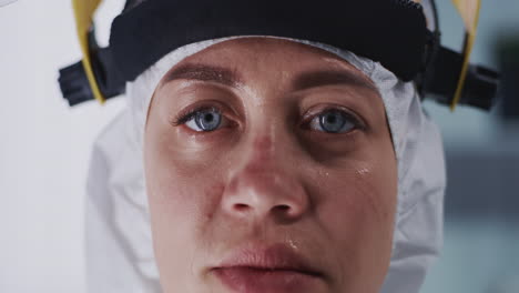 sweaty female doctor looking at camera sweaty woman in hazmat suit looking at camera during break in coronavirus hospital