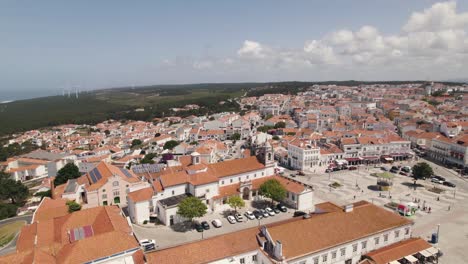 aerial ascending sanctuary of nossa senhora da nazaré on the hilltop, rooftops on cityscape