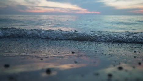 pequeñas olas de agua ruedan hacia la orilla en cámara lenta en una hora dorada nublada