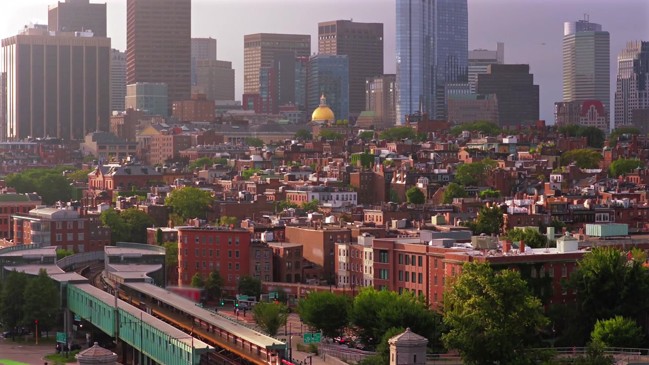 Långsamt stigande flygvy över Bostons Beacon Hill vid soluppgången, med Massachusetts State House gyllene kupol, historiska tegeltak, Longfellow Bridge och stadssilhuetten mot öster.