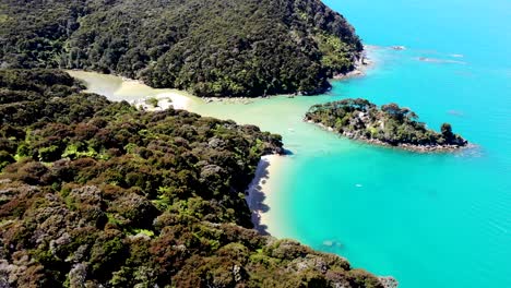 Aerial-view-of-boat-sitting-in-clear-water-bay-surrouned-by