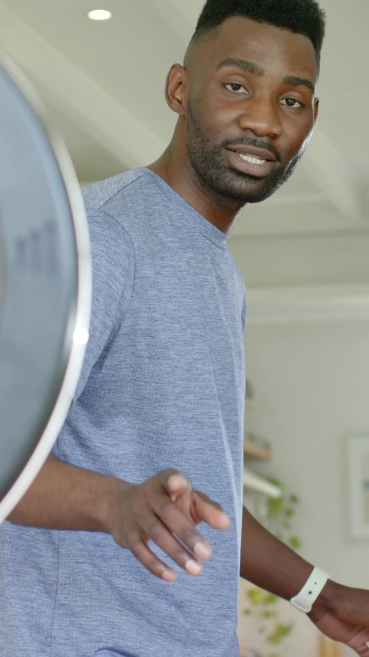 Vertical video: Directing man in blue tee guiding cohost entering at home for filming, ring light