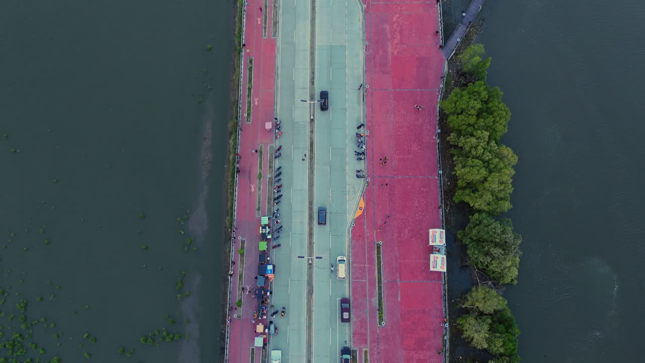 Drone footage of a busy riverside road with cars, people, and colorful stalls in the Philippines. Perfect for urban lifestyle, transportation, and travel projects