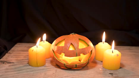 Calabaza-De-Halloween-Con-Velas-Encendidas-En-Madera-En-El-Fondo-De-Una-Habitación-Oscura