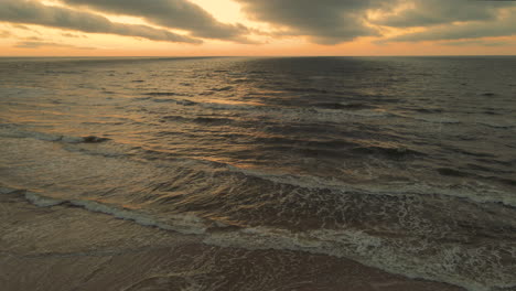 Vista-Aérea-De-La-Puesta-Del-Sol-De-Las-Olas-Rompiendo-En-La-Costa,-Espectacular-Paisaje-Marino,-Disparo-De-Drones