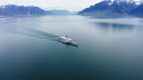 wide drone shot of passenger paddle steamer boat transporting passengers across a lake in switzerland with birds flying past