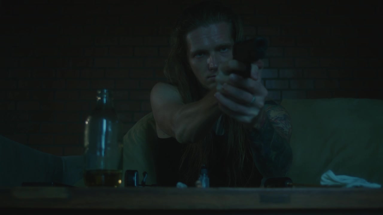 Man Cleaning and Aiming a Handgun in a Dimly Lit Room