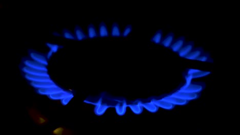 Gas-burning-from-a-kitchen-gas-stove,-dark-background,-cold-winter-and-energy-crisis-concept,-closeup-shot