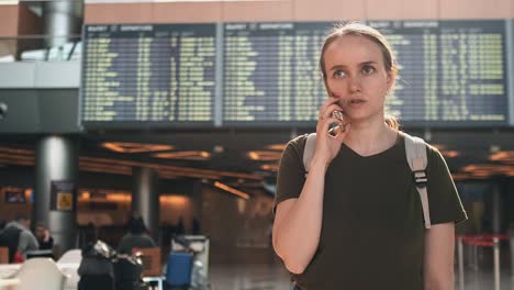 joven hermosa de pie en el aeropuerto llamando por teléfono