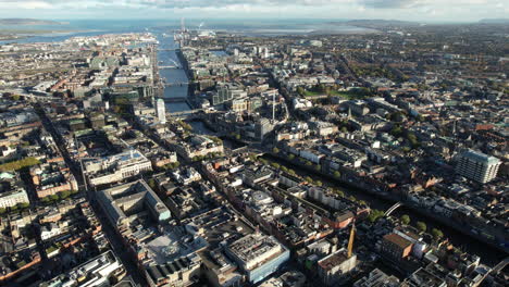 downtown dublin, ireland, high rise aerial view of cityscape, buildings, liffey river and skyline on bay on sunny day, drone shot