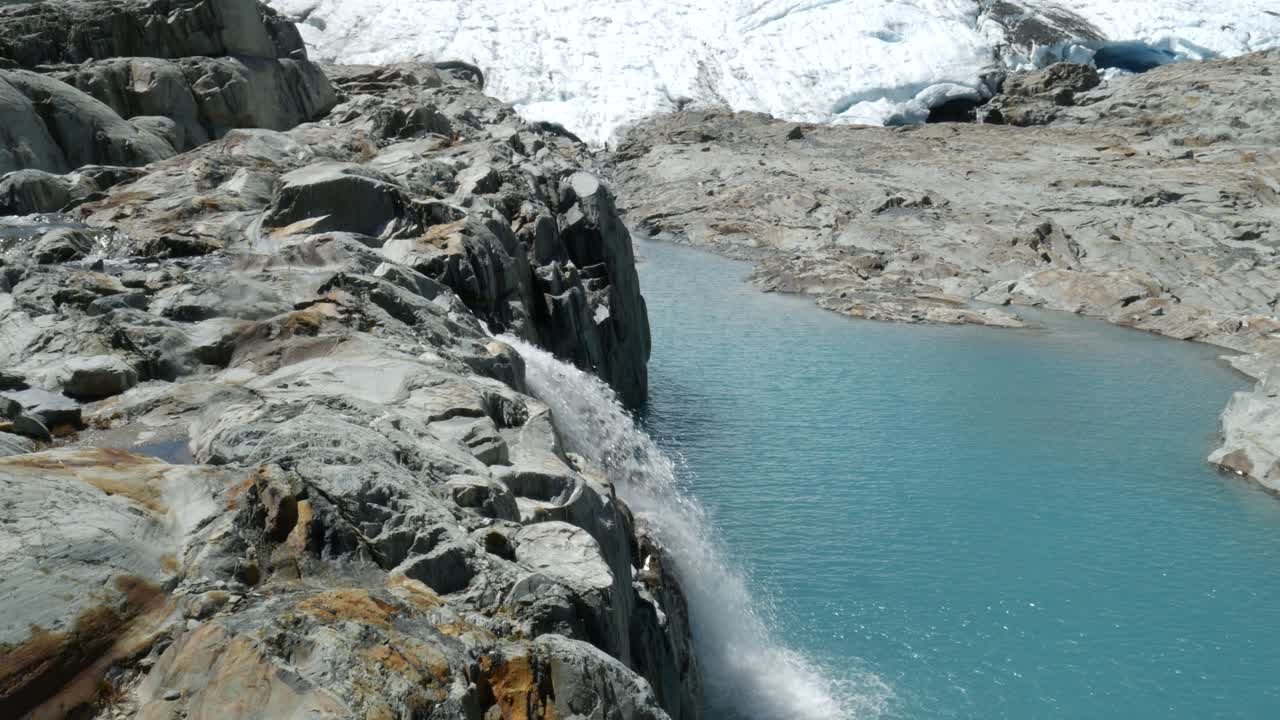 snowmelt waterfall flowing into blue lake