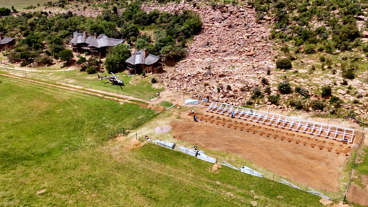 Aerial view, energy team installing solar panels at remote African safari lodge