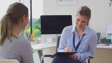 Woman-Doctor-Or-GP-In-Office-Meeting-Teenage-Female-Patient-For-Appointment