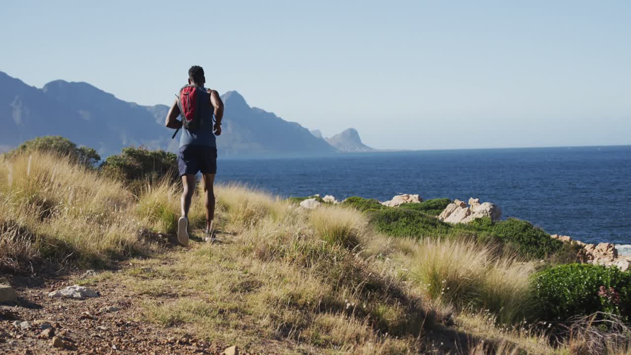 hombre afroamericano de cross country corriendo en el campo por la costa