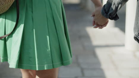 closeup of young couple walking with intertwined fingers.